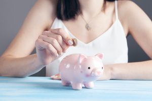 Woman puts coins in a piggy bank