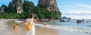 woman on beach in front of boats with arms spread out