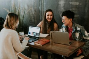 Group of people with laptops sat around a table laughing