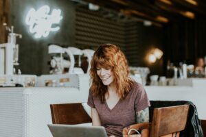 woman working in a cafe smiling at her laptop