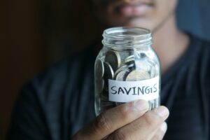 Man holding jar of coins labelled 'savings'