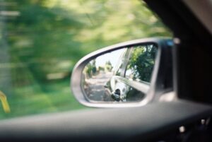 car wing mirror reflecting blind spot on country road