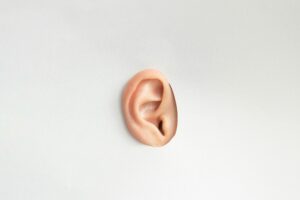 An ear poking through a hole in a white wall