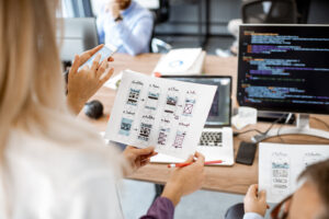 Woman holding web design on paper with screen in the background