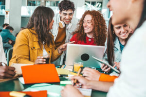 Students gathered around a laptop smiling.