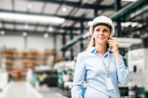 Woman in hardhat on phone in warehouse